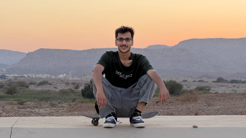 Skateboarding in Oman: Firas Ahmed crouches on his board above the desert hills at sunset. Photo by Mike Boisvert / The Skate Nomad