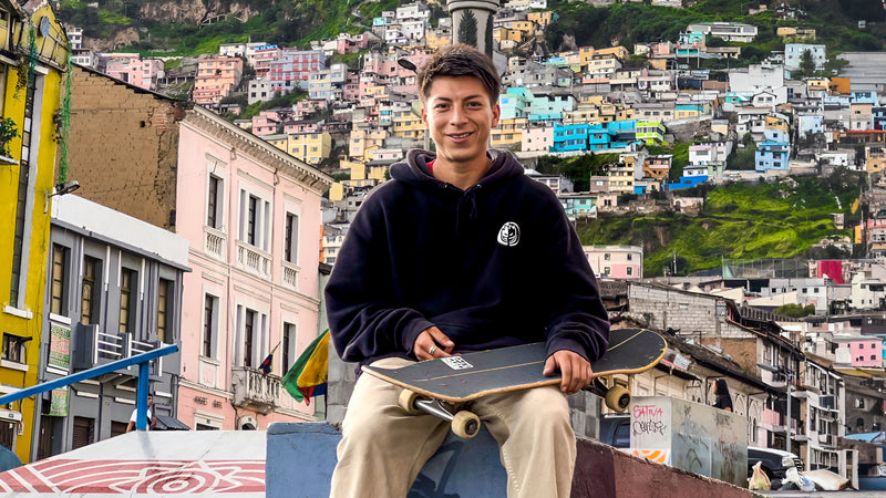 Skateboarding in Quito, Ecuador: a local skater sits with his board in front of the colourful houses on Quito's hills. Photo by Mike Boisvert / The Skate Nomad