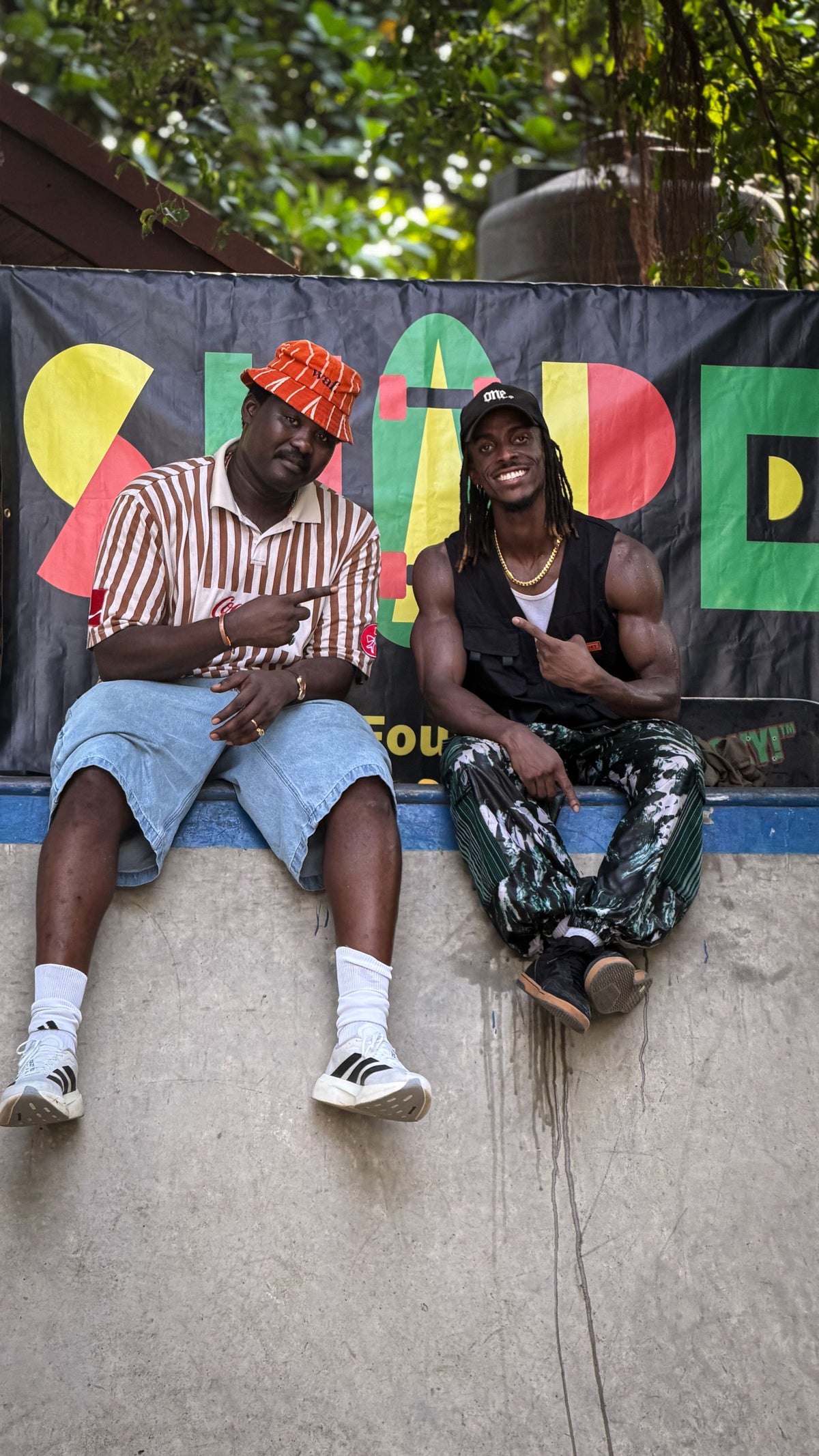 Skateboarding in Nigeria: two skaters sit on a ramp under the Shape Skate Foundation banner. Photo by Mike Boisvert / The Skate Nomad