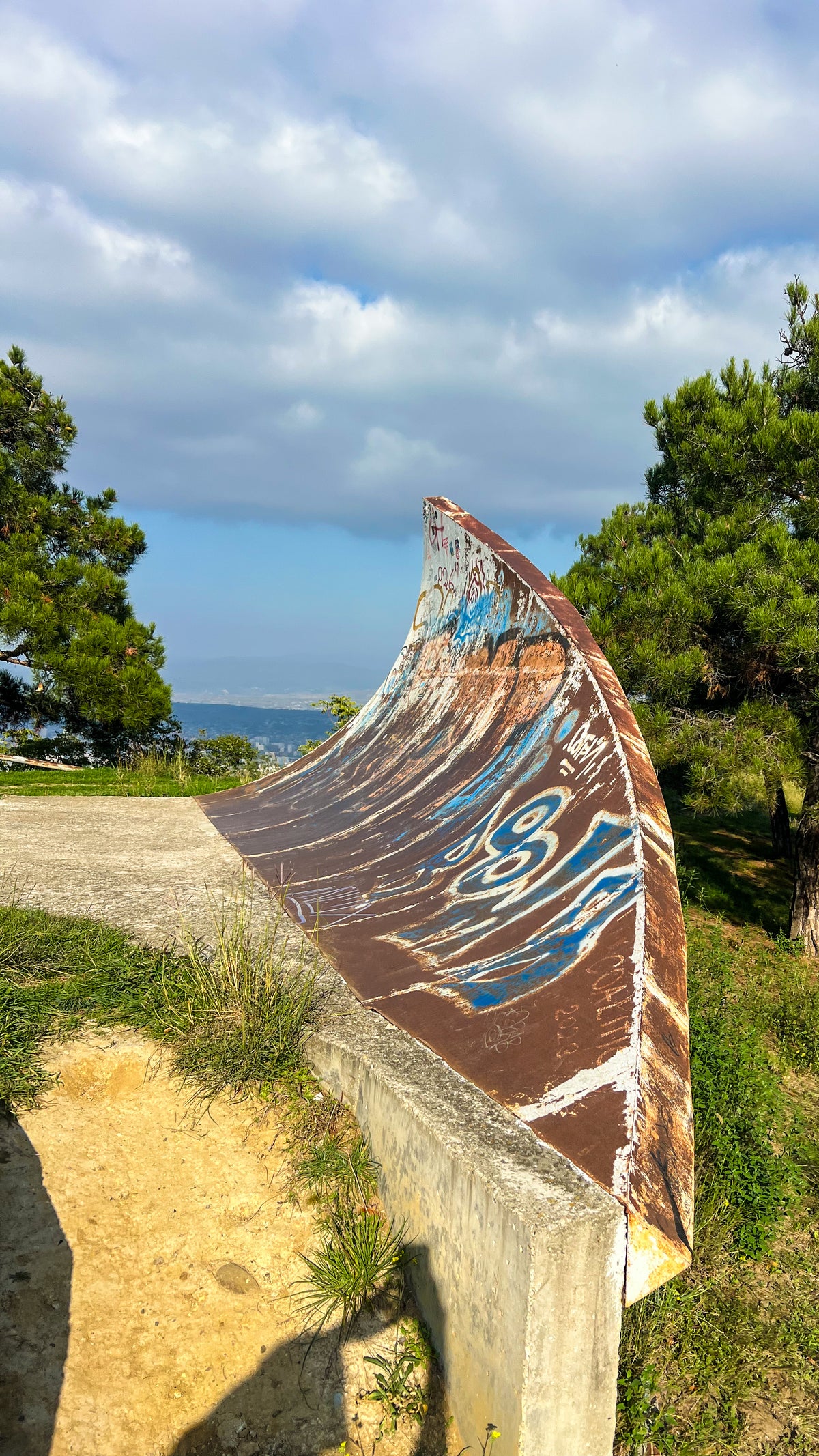 Georgia: a graffiti-covered curved concrete wall on a grassy hilltop among pine trees. Photo by Mike Boisvert / The Skate Nomad