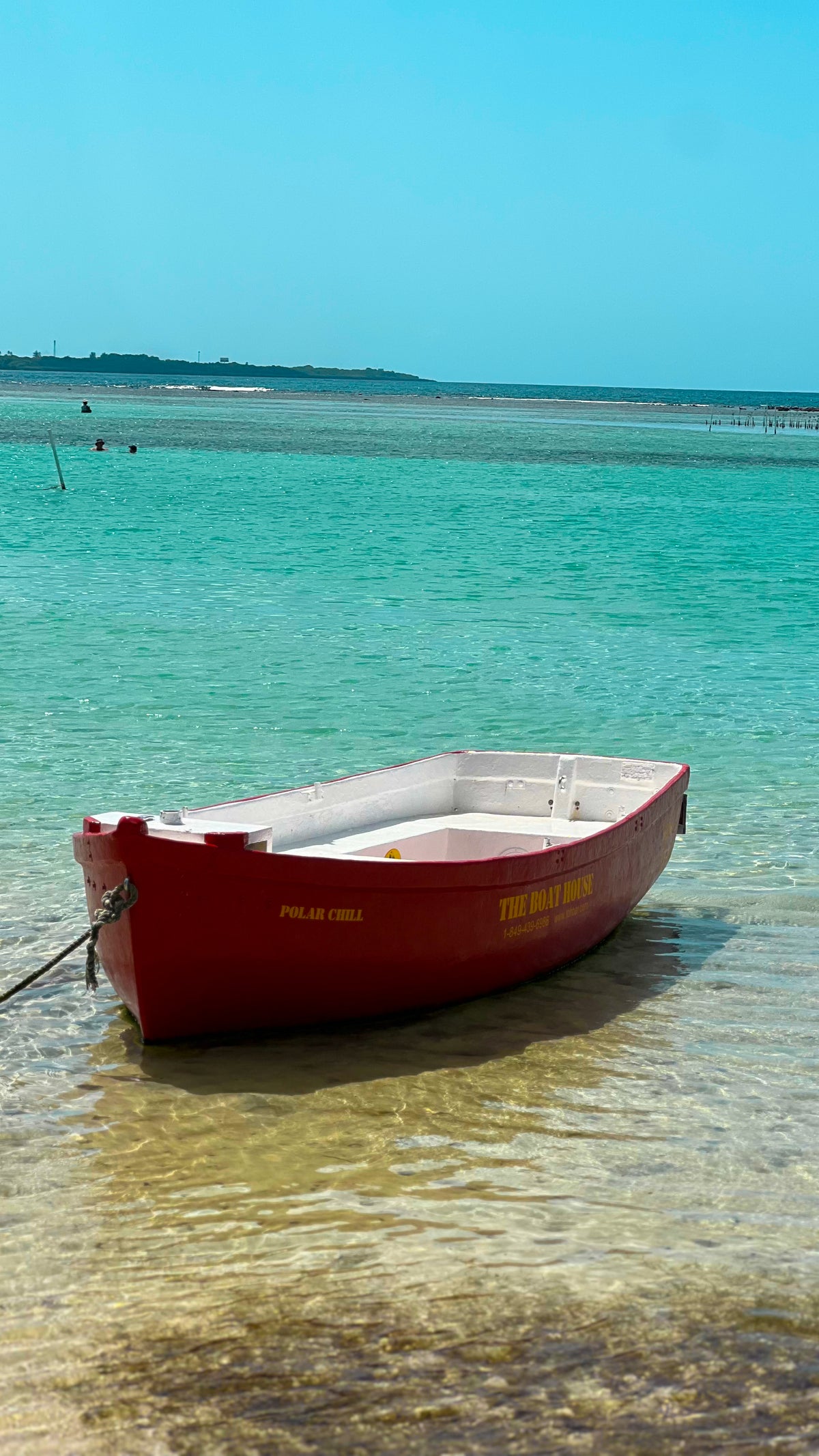 Dominican Republic: a small red boat in clear turquoise water off a sandy beach. Photo by Mike Boisvert / The Skate Nomad