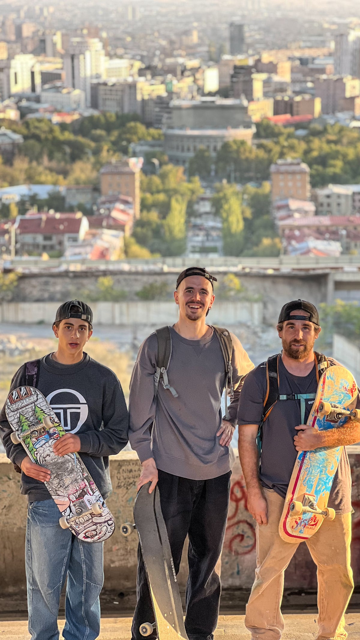 Skateboarding in Armenia: three skaters pose with their boards on a terrace high above the city. Photo by Mike Boisvert / The Skate Nomad