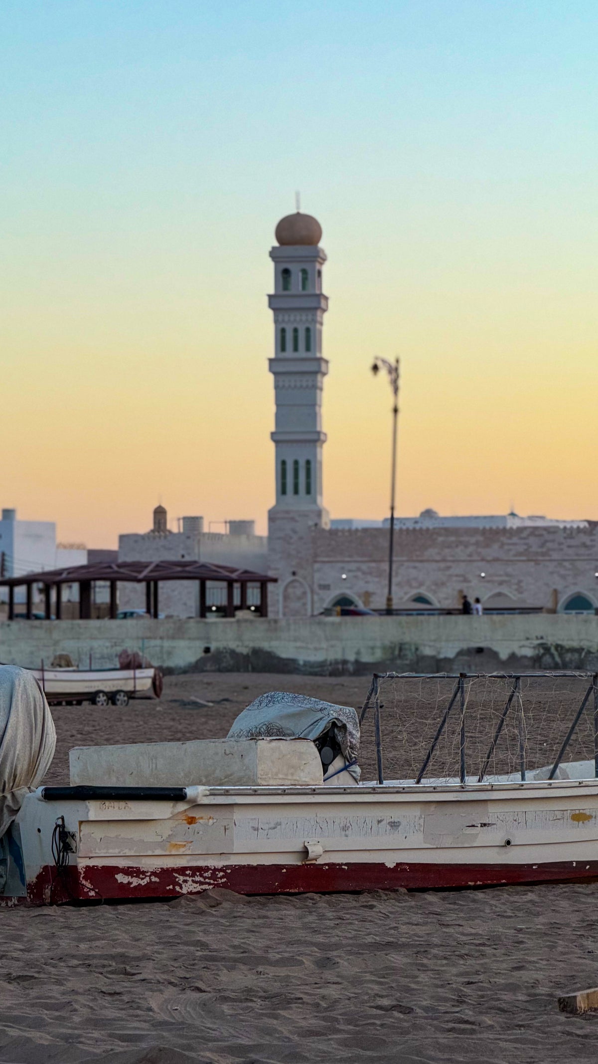 Oman: a minaret and fishing boats on the beach at sunset. Photo by Mike Boisvert / The Skate Nomad
