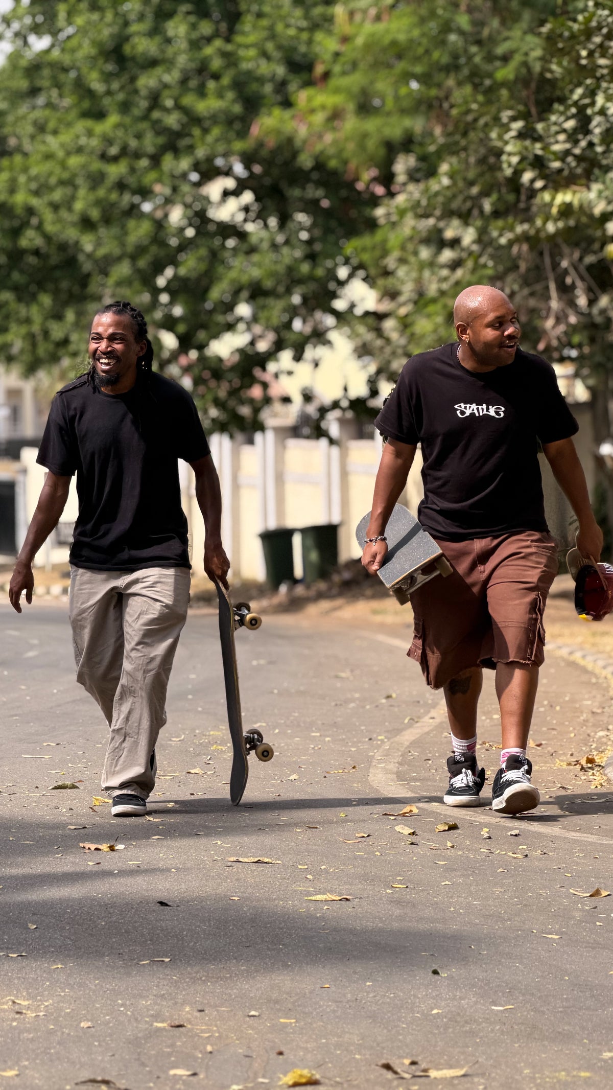 Nigeria: two skaters walk down a quiet street, board in hand. Photo by Mike Boisvert / The Skate Nomad