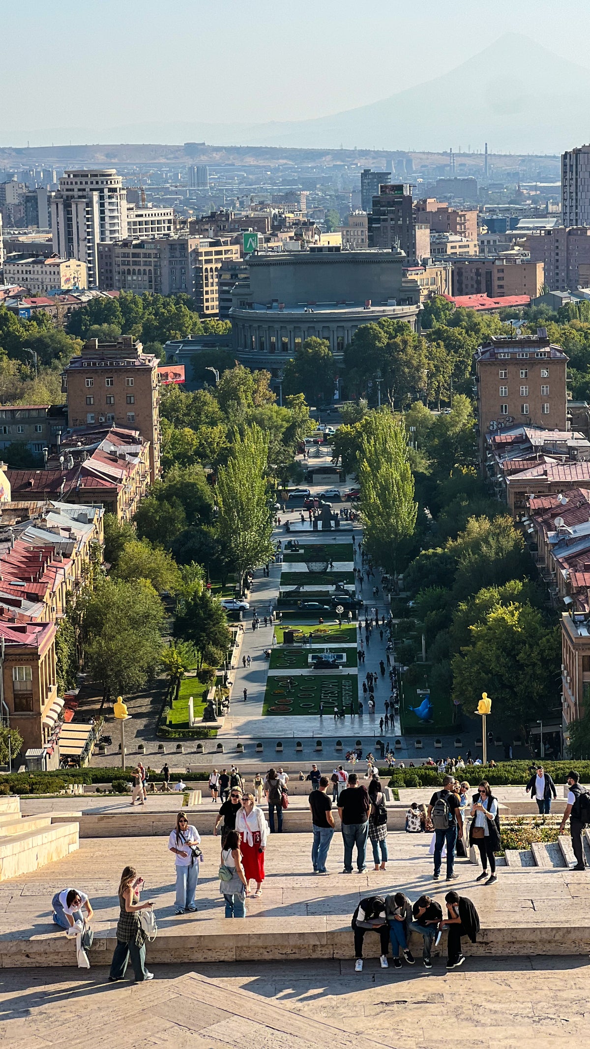Armenia: people at the top of a long stepped terrace looking down a green avenue into the city. Photo by Mike Boisvert / The Skate Nomad
