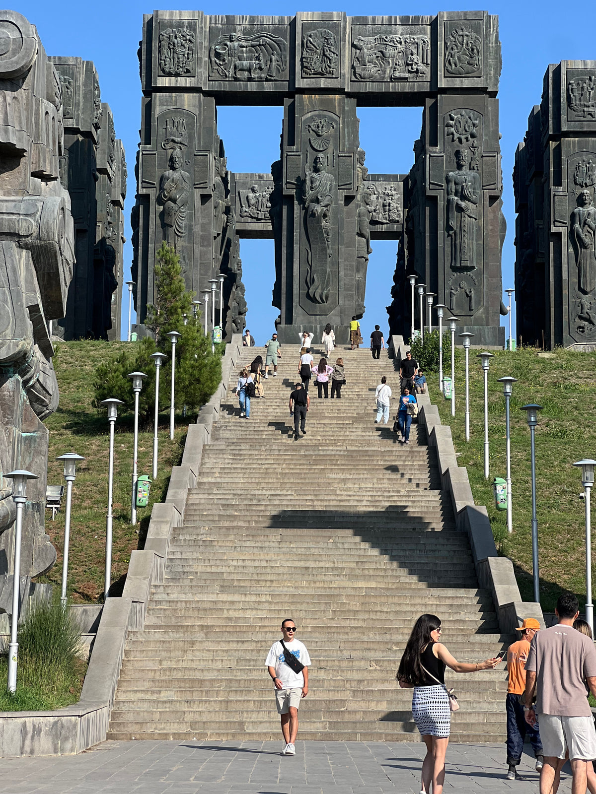 Georgia: visitors climb a long stone staircase toward the giant carved pillars of a monumental sculpture. Photo by Mike Boisvert / The Skate Nomad