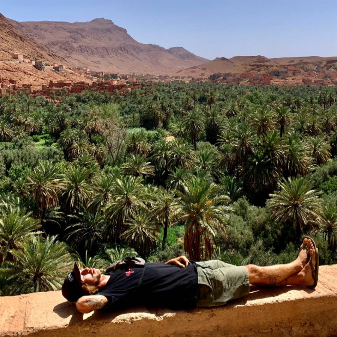 Morocco: Mike Boisvert lies on a wall above a palm oasis in the mountains. Photo by Mike Boisvert / The Skate Nomad