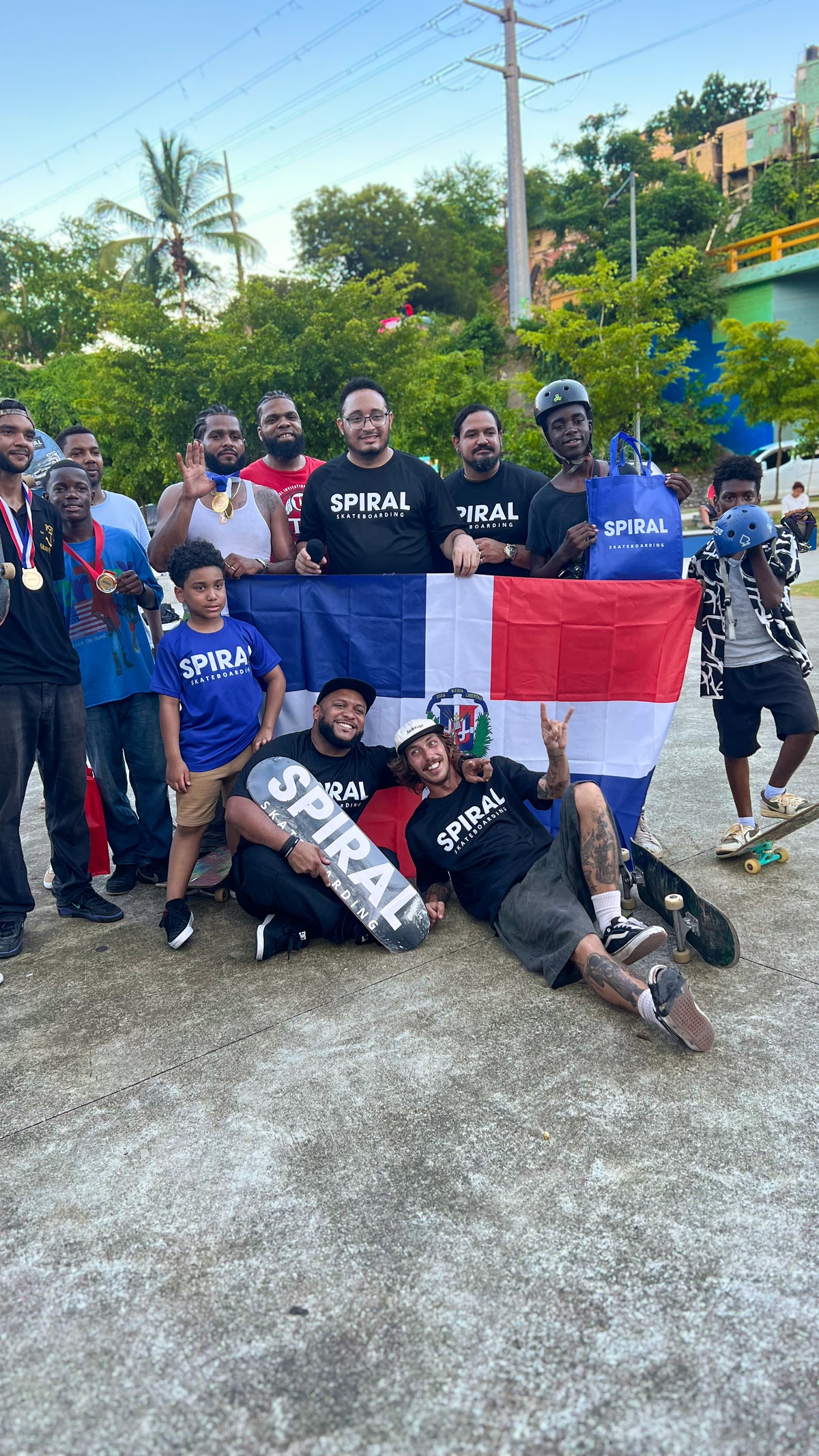Skateboarding in the Dominican Republic: skaters in Spiral Skateboarding shirts, some wearing medals, pose with a Dominican flag. Photo by Mike Boisvert / The Skate Nomad