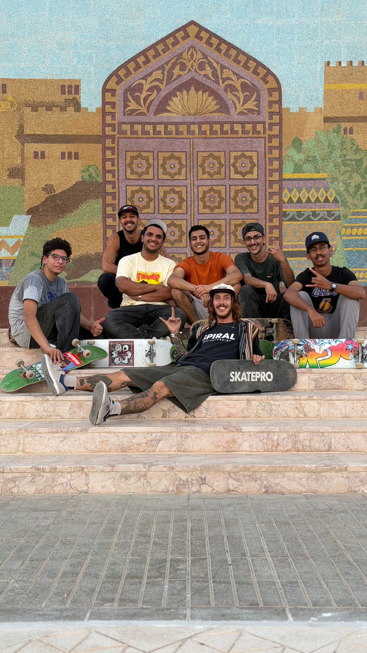 Skateboarding in Oman: the crew sits on the steps in front of a mosaic wall. Photo by Mike Boisvert / The Skate Nomad