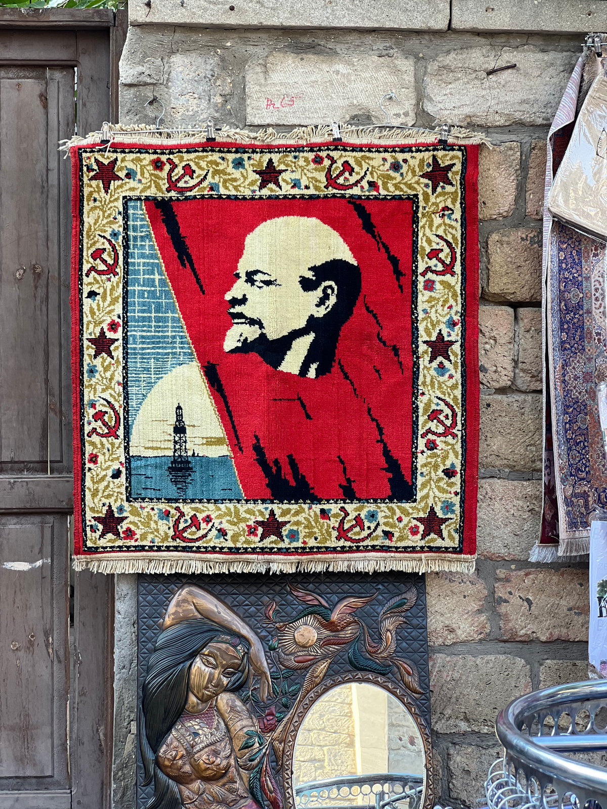 Baku, Azerbaijan: a Soviet-era carpet with a portrait of Lenin hangs on an old stone wall next to other carpets. Photo by Mike Boisvert / The Skate Nomad