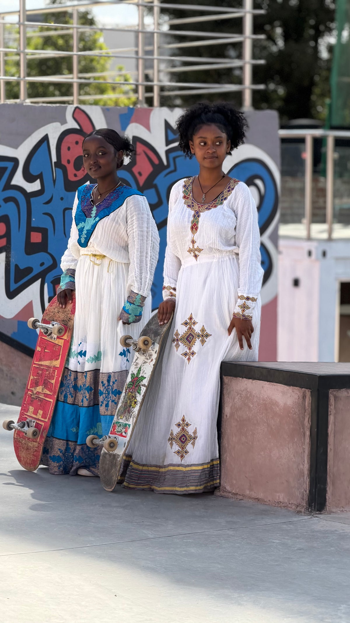 Skateboarding in Addis Ababa, Ethiopia — two skaters in habesha dresses in front of the graffiti wall — photo by Mike Boisvert / The Skate Nomad